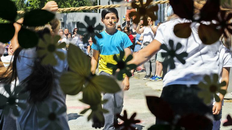 A boy, wearing the blue and yellow Ukrainian national colours, walks through a crowd of people.