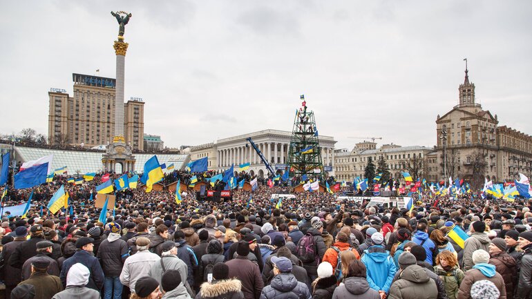 Maidan Square in Kiev, recognisable by the large white pillar with the angel, is full of people waving Ukrainian flags.